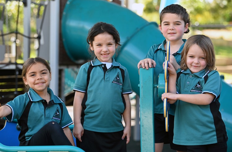 4 students smiling on the play equipment
